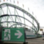 Notausgangsbanner rechts - als Fluchtwegleitsystem auf Volksfesten Notausgangsbanner mit Pfeil nach rechts am Bauzaun vor Achterbahnkonstruktion auf einem Volksfestgelände
