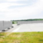 Gewebeplane günstig weiß - randverstärkt und hoch reißfest Weiße Gewebeplane als Wind- und Sichtschutz an Bauzaunelementen auf einem Freigelände mit Rasen und befestiger Fläche