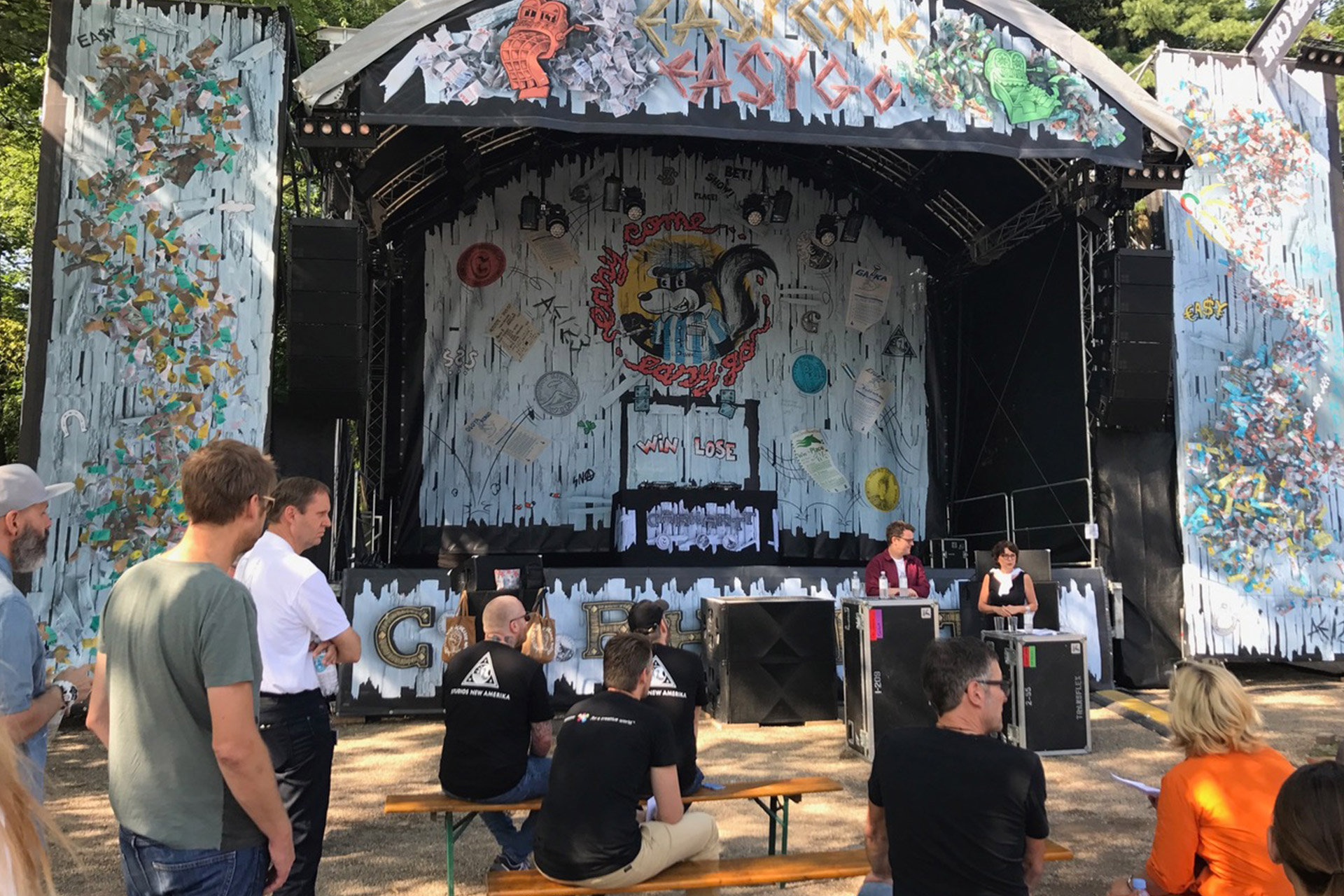 Kleine Festivalbühne mit vollflächiger Bühnenverkleidung aus Netzvinyl mit künstlerischem Design und Publikum davor