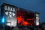 Meshbanner - konfektioniert und bis zu 4,9 m Breite nahtlos bedruckt Festivalbühne mit Header und zwei Portalflächen aus Netzvinyl mit G.O.N.D. Motiv, Publikum davor bei Abendstimmung