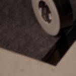 Messeteppich Rollenware grau meliert - einfache Verlegung auf Messen Teils verklebte Ecke eines grau-melierten Rips Teppichs, darauf eine schräg stehende Klebebandrolle