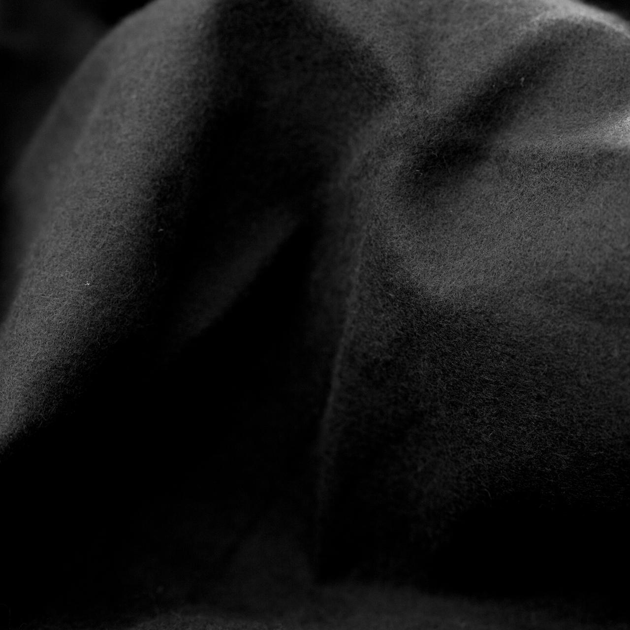 Bildfüllende Nahaufnahme eines schwarzen Dekomoltons mit angerauter, matter Oberflächenstruktur