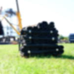 Gummiläufer Standard im Rollenformat - ideal für Veranstaltungen Eine Palette mit gestapelten Rollen Gummimatten auf einer Wiese, im Hintergrund Bühnenaufbau für ein Festival