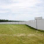 Gewebeplane günstig weiß - wind- und wasserdichte Plane aus Polyethylen Weiße Bauzaunblenden als Sichtschutz an einer langen, nach links gebogenen Bauzaunreihe auf offenem Rasengelände