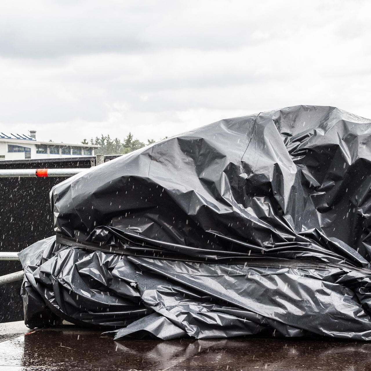 Universal Gewebeklebeband fixiert eine Abdeckplane über einem Gegenstand auf einer Bühnenfläche bei Regen