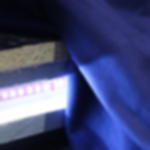 Dekomolton B1 - schwer entflammbarer Stoff für Lichtinstallationen Nahaufnahme eines blauen Molton Stoffes über einer Bühnenkante, daneben LED-Lichtband in Weiß, das den Stoff anstrahlt