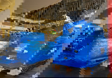 Vorschau Blau verpackte 'allbuyone'-Pakete auf Paletten in einer Halle.