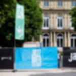 Bauzaunfahne mit Piktogramm Notausgang zertifiziert nach DIN EN 7010 Bauzaunfahne mit Notausgangs-Piktogramm und Pfeil nach unten bei Jazz Open Stuttgart, montiert am Bauzaun