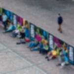 Bauzaunbanner Mesh 3,41 x 1,76 m - ideal für Werbung am Bauzaun Werbebanner aus Mesh mit individuellem Aufdruck an Bauzäunen, Personen lehnen sich entspannt auf dem Boden sitzend an