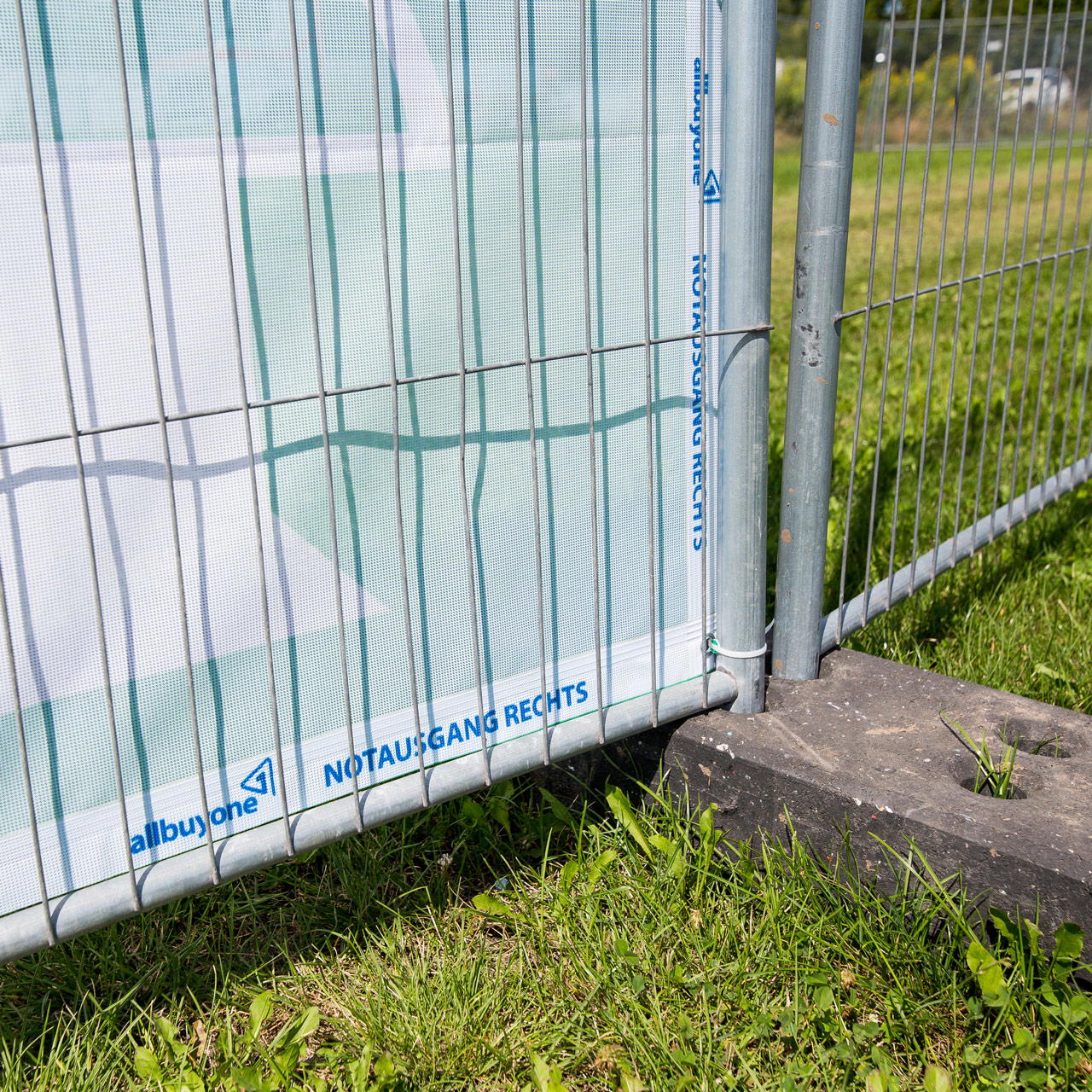 Unterer Bereich der Rückseite eines Notausgangsbanners mit Aufdruck „Notausgang rechts“ befestigt am Bauzaun 