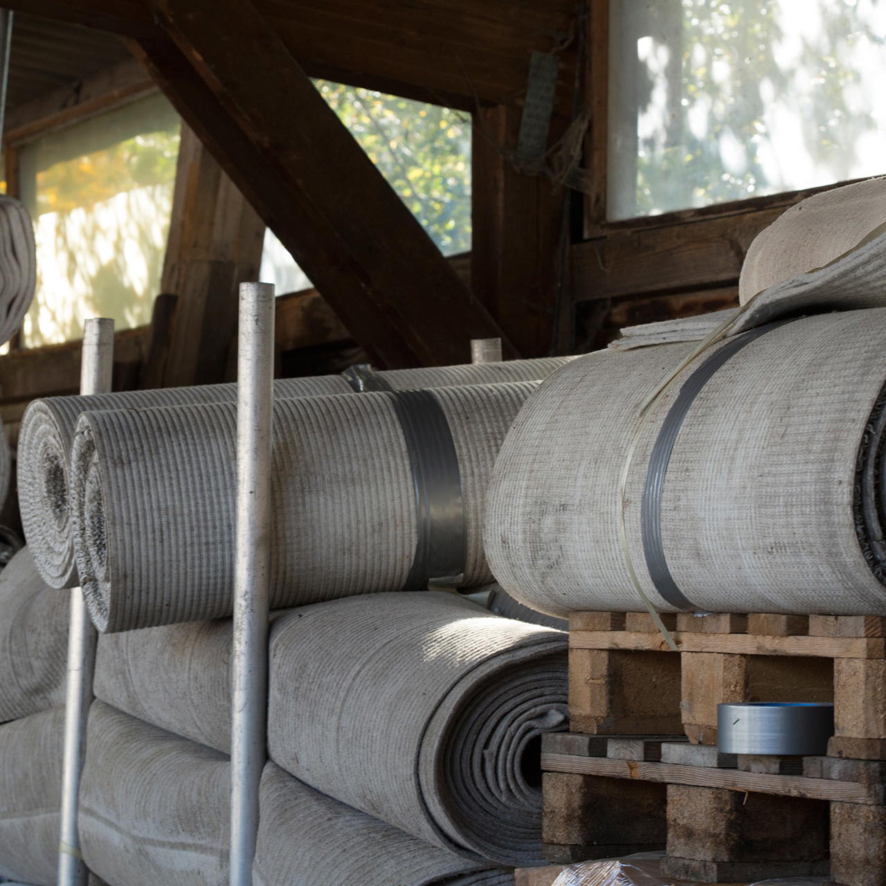 Mehrere liegende Rollen Teppich fixiert mit schwarzem Panzertape zur Formstabilisierung bei der Lagerung auf Paletten