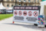 Meshbanner - individuell bedruckte Bauzaunbanner für Events Geöstes Banner aus Netzvinyl mit Kabelbindern an Bauzaun befestigt mit Zugangshinweisen auf einem Open-Air-Event