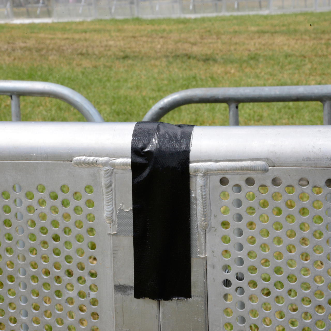 Schwarzes Gewebeklebeband verbindet zwei Gitterelemente an der Oberkante einer Barrikade durch vertikale Verklebung