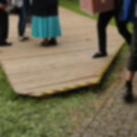 Warnmarkierungsband GT 571 schwarz-gelb - Profi Klebeband mit hoher Soforthaftung Im Außenbereich verlegte Holzbodenfläche mit gelb-schwarzem Gewebewarnband an erhöhter Kante bei einer Veranstaltung