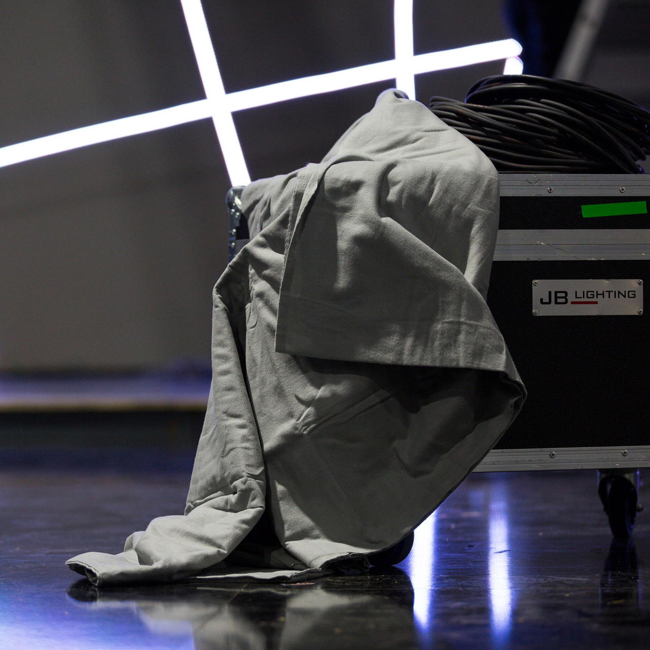 Grauer Dekorations Molton locker über ein Flightcase gelegt und daneben ein zusammengerolltes Kabel für Lichttechnik