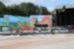Frontlit PVC - als Kulisse und Verkleidung für Bühnen und Zäune Künstlerisch bedruckte Frontlit PVC Banner mit Landschaftsmotiv beim Befestigen an Gerüstkonstruktion auf Festival