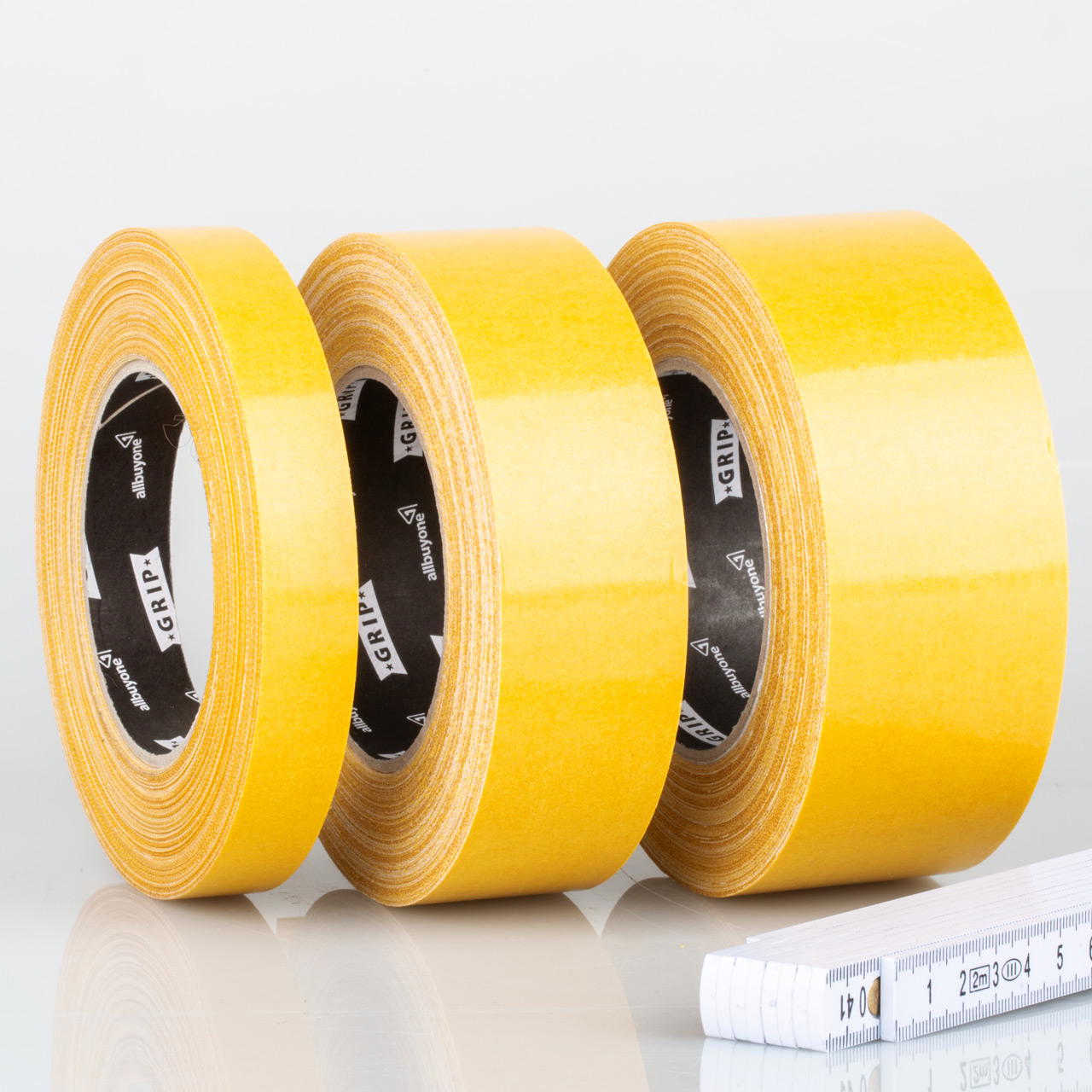 Drei nebeneinander stehende Rollen beidseitiges Klebeband GT 703 mit gelber Abdeckung in unterschiedlichen Breiten