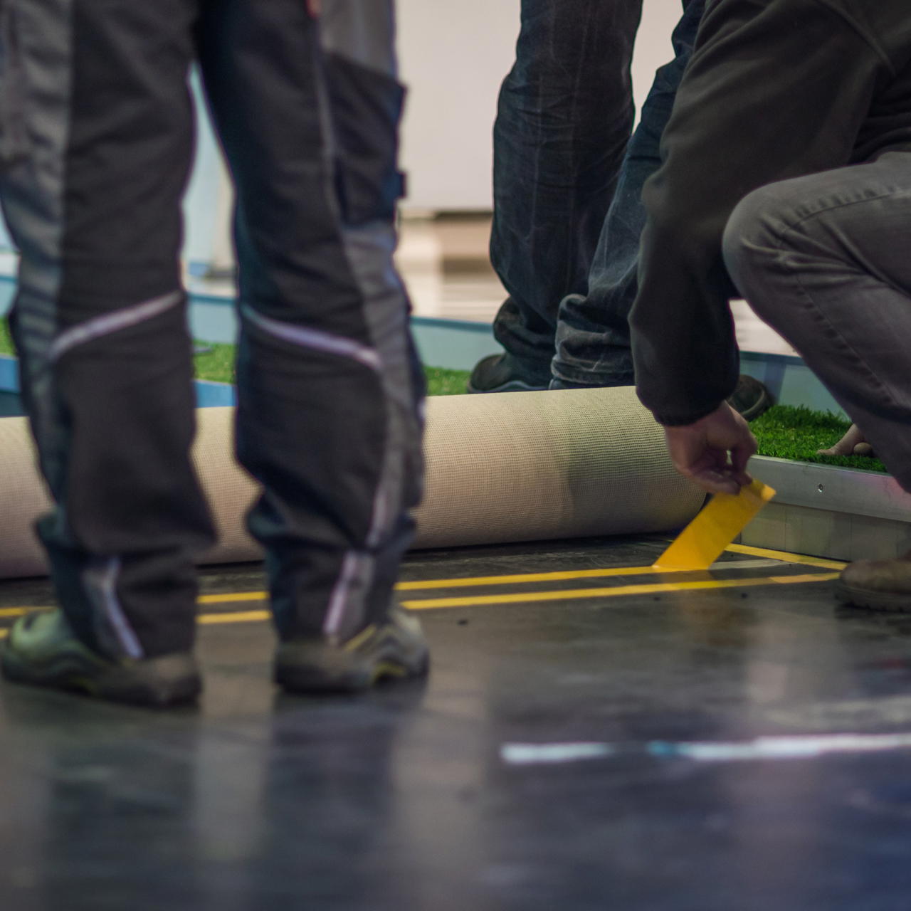 Arbeiter entfernt die Papierabdeckung von Gewebeband GT 703 zur Verklebung einzelner Teppichbahnen bei Eventaufbau 