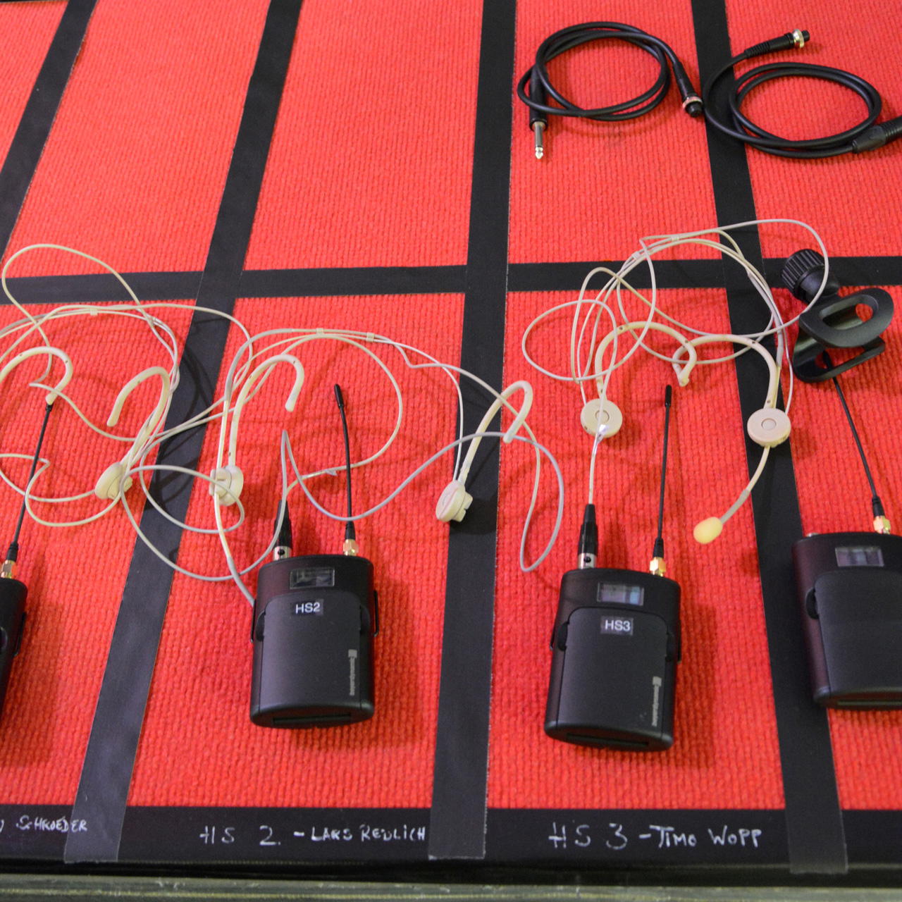Schwarzes Gewebeklebeband als Flächenmarkierung zur Organisation von Mikrofonsets auf roter Teppichunterlage