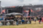 Frontlit PVC - individuelle Bühnen-Banner und Header für Festivals Festivalbühne beidseitig mit schwarz-oranger Frontlit PVC Verkleidung und Bühnen-Header, Bar und Zuschauer davor