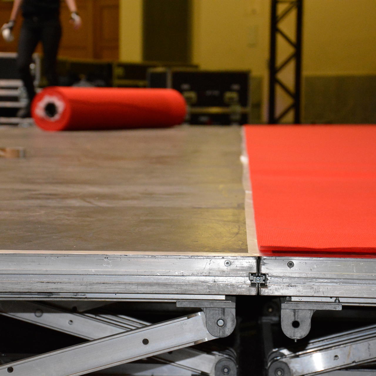 Roter Teppich auf mobiler Bühne verlegt, bündig daneben sichtbar eine zweite vorbereitetet Klebefläche aus GT 703 