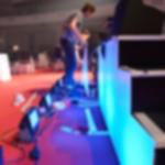 Dekomolton B1 - als Wandbespannung für Bühnen und Messen Personen verkleiden eine Bühnenkante mit weißem Dekomolton, der von unten mit LED-Flutern in Blau angestrahlt wird