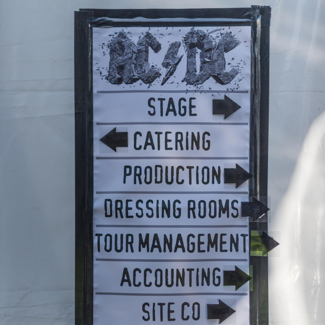 Schwarzes Universal Gewebeband mit hoher Klebkraft fixiert ein Hinweisschild vierseitig auf einer weißen Zeltplane 