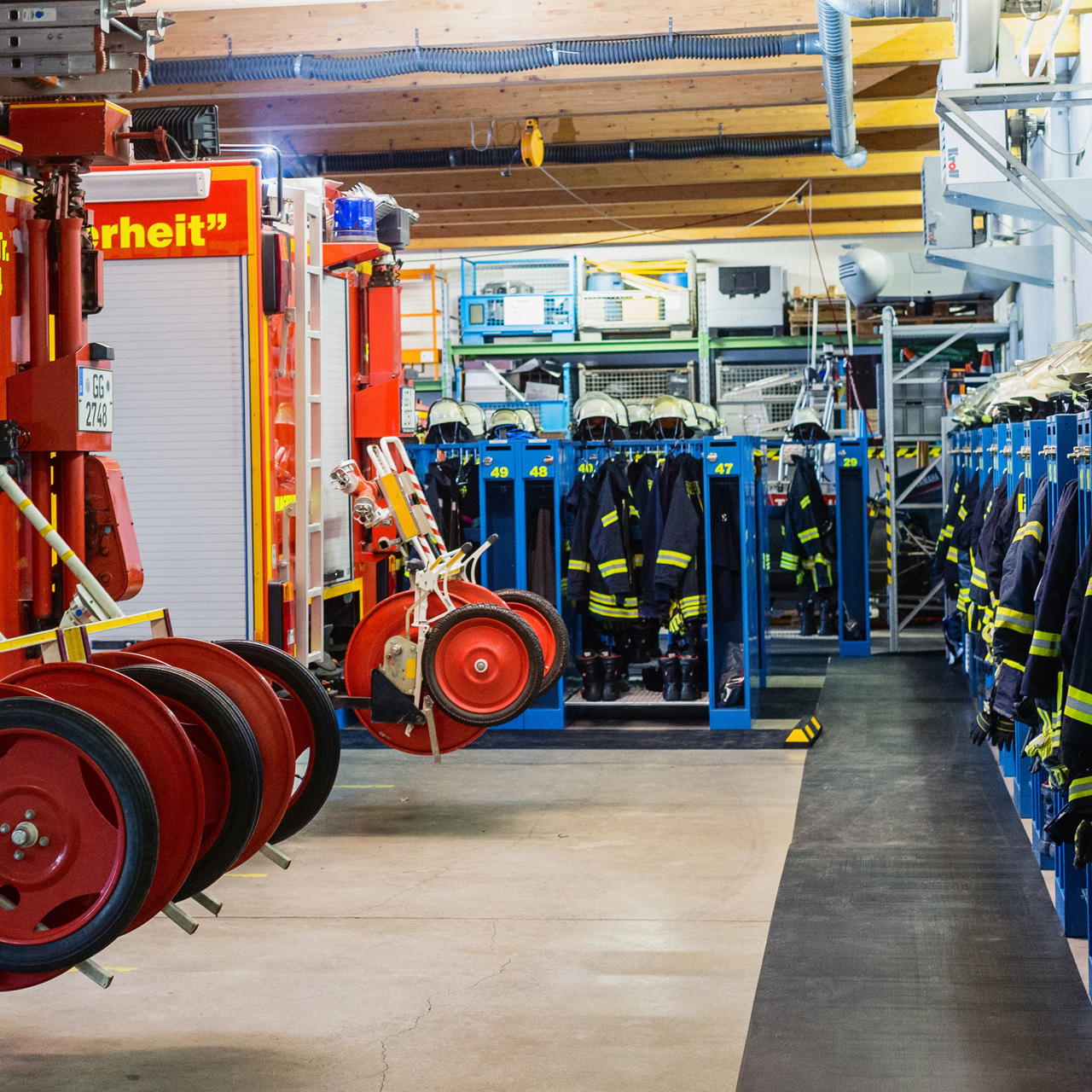 Gummimatte als rutschhemmender Bodenbelag in einem Feuerwehrgerätehaus neben Einsatzkleidung und Schlauchwagen
