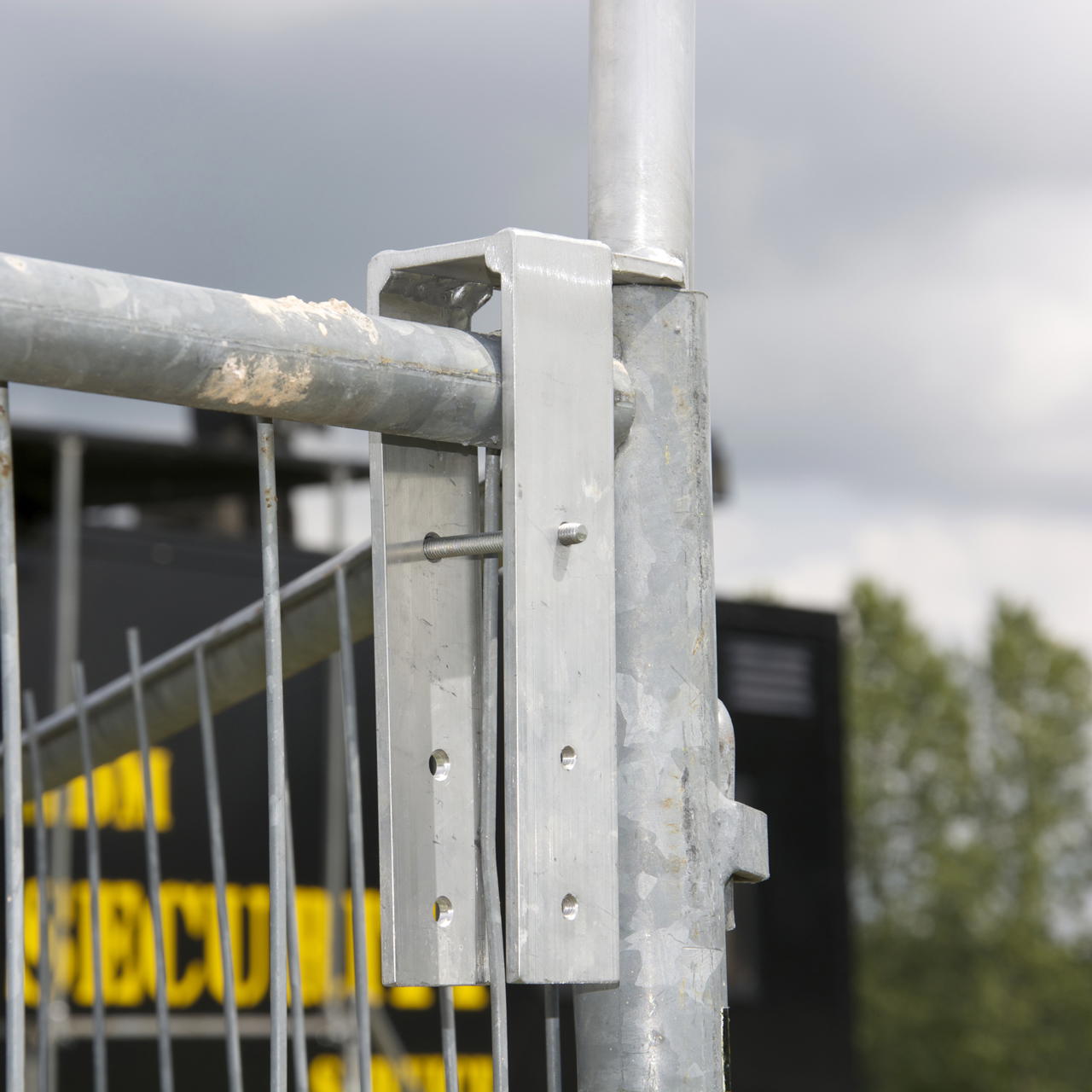 Metalladapter zur sicheren Montage einer Notausgangsfahne am Bauzaun, mit Sicherungsstift an Mobilzaunrahmen montiert