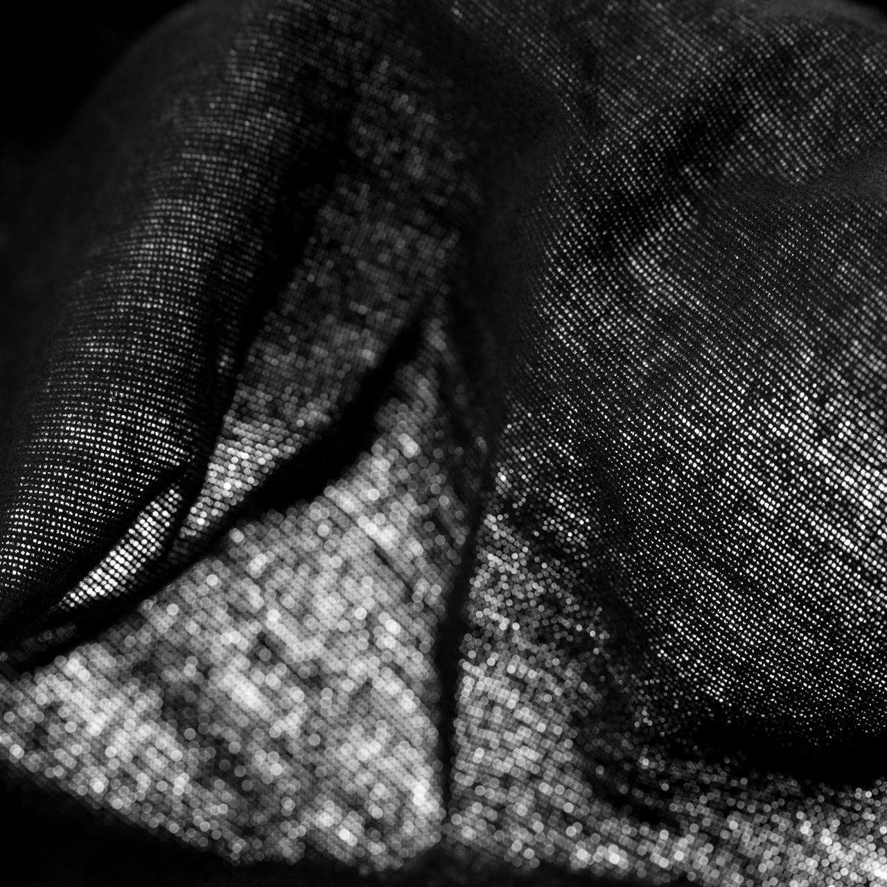 Bildfüllende Nahaufnahme eines locker gehängten, schwarzen Dekomoltons mit ungleichmäßger Hinterleuchtung