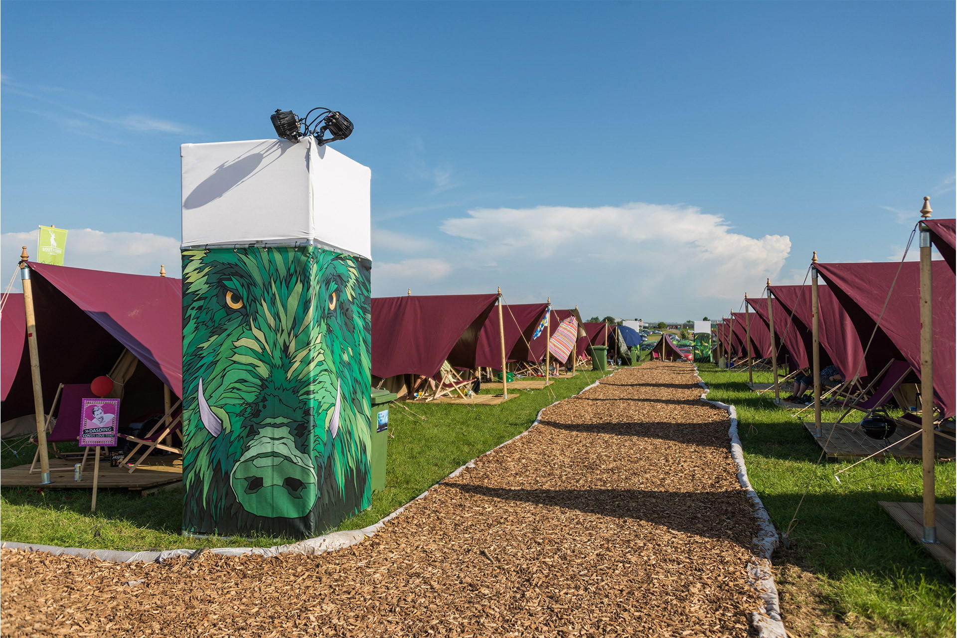 B1 Frontlit Plane als Branding mit Wildschweinmotiv bedruckt auf Festival-Zeltplatz zwischen burgunderfarbenen Zelten 