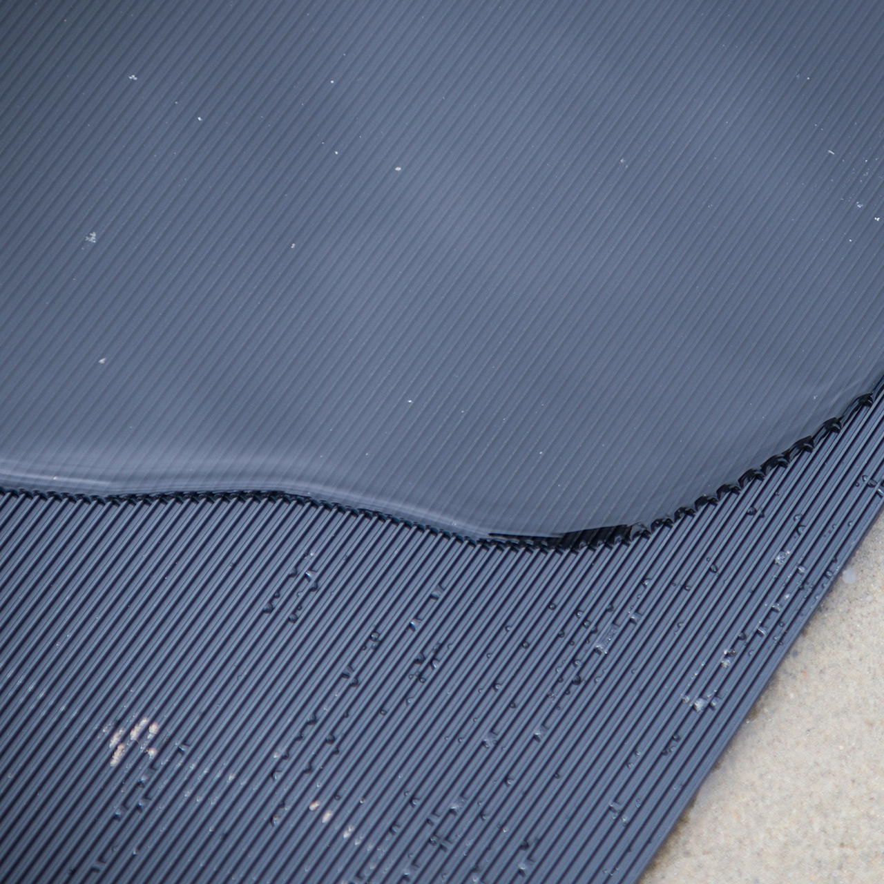 Versetzt übereinander liegende Gummimatte mit sichtbarer fein geriefter Oberseite und feinnoppiger Rückseite