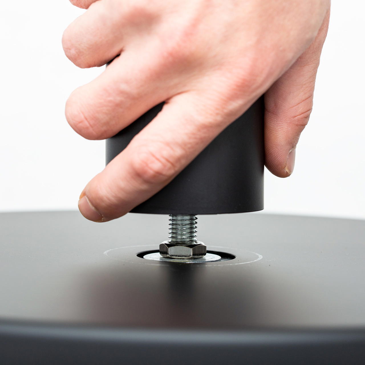 Nahaufnahme einer Hand, die einen Gurtpfosten auf eine durch den Bodenteller geführte M12 Schraube dreht