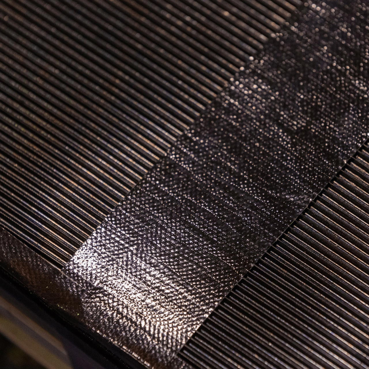 Nahaufnahme eines Streifens schwarzen Duct Tapes glatt und exakt auf einer Feinriefenmatte verklebt