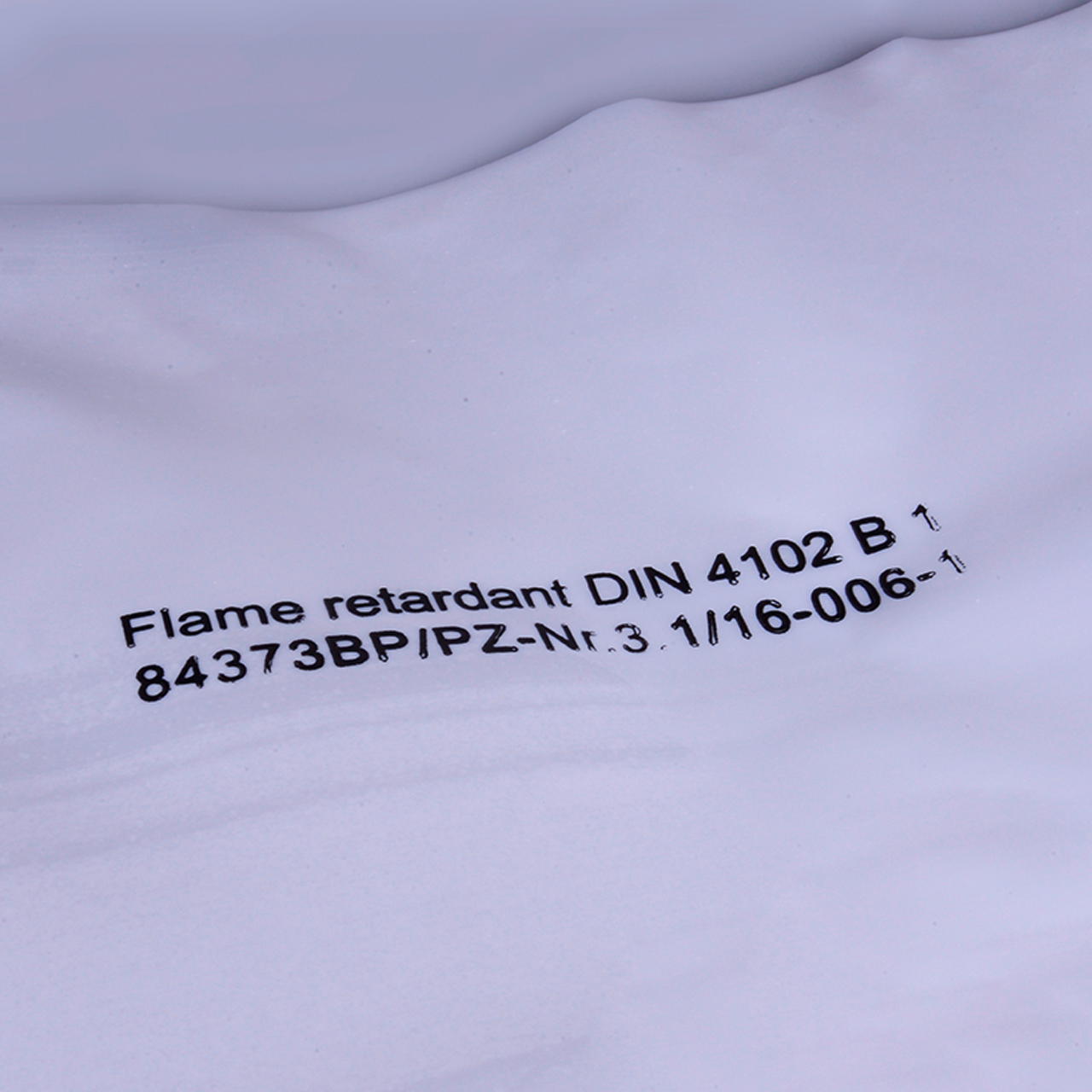 Nahaufnahme einer weißen B 1 Folie mit schwarzem Aufdruck zur Zertifizierung der Schwerentflammbarkeit nach DIN 4102 B1