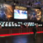 Messeteppich Rips B1 - ideal als Empfangsteppich für VIP Events Roter Rips gesäumt mit Absperrpfosten vor einem Gaming-Messestand mit Monitorreihen, Großbildschirm und Game-Grafik
